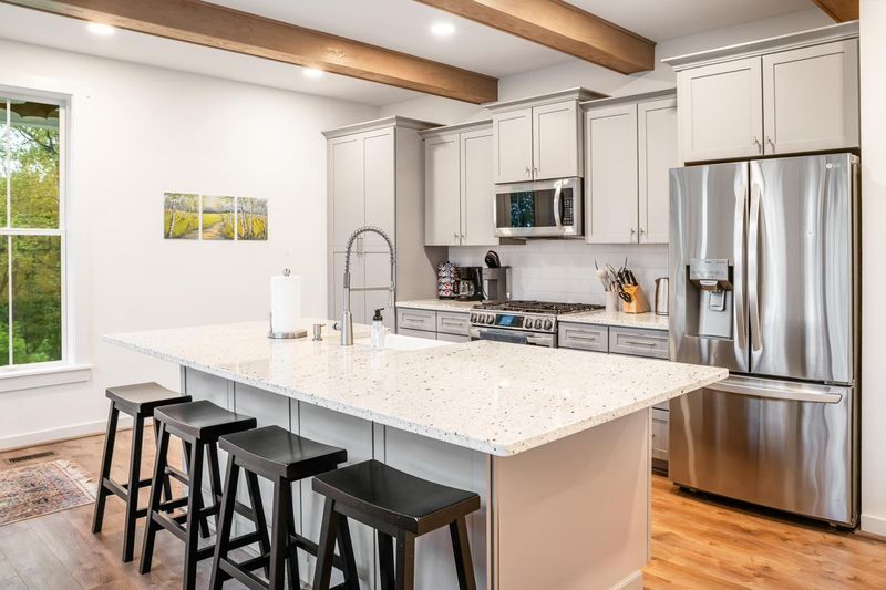 The kitchen, with a large stone island, bar stools and stainless appliances
