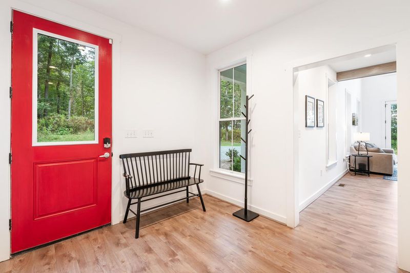 The red front door, with a bench and coat stand in the entry